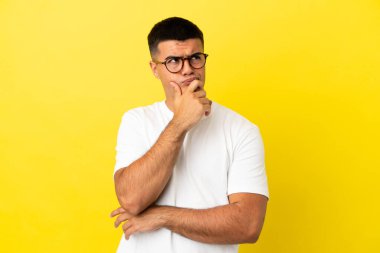 Soyutlanmış sarı arka planda genç yakışıklı bir adam. Şüpheleri var ve kafası karışık.