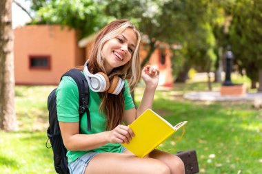 Dışarıda elinde bir defter tutan genç bir kız öğrenci.