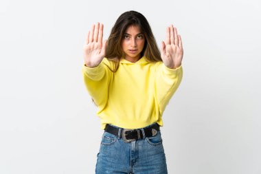 Beyaz arka planda izole edilmiş genç beyaz kadın dur hareketi yapıyor ve hayal kırıklığına uğruyor.