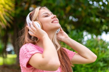 Açık havada müzik dinleyen genç ve güzel bir kadın.