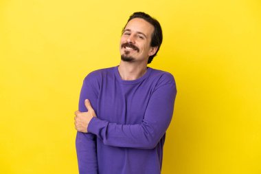 Sarı arka planda izole edilmiş genç beyaz adam gülüyor.