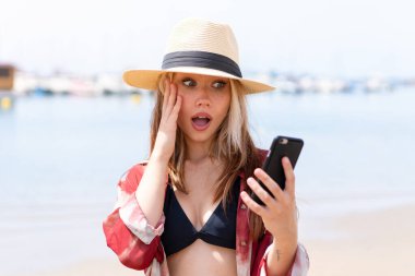 Yaz tatilinde genç ve güzel bir kadın sahilde selfie çekiyor.