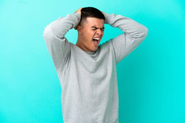 Soyutlanmış mavi arka planda genç yakışıklı bir adam stresli