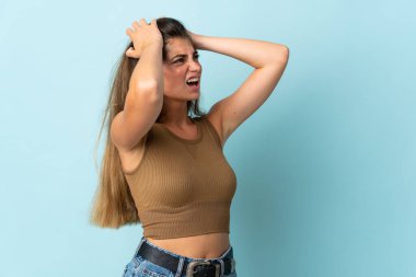 Mavi arka planda izole edilmiş genç beyaz kadın bunalımda.