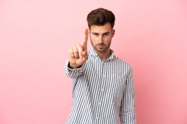 Pembe arka planda izole edilmiş beyaz tenli yakışıklı adam ciddi bir ifadeye sahip birini sayıyor.