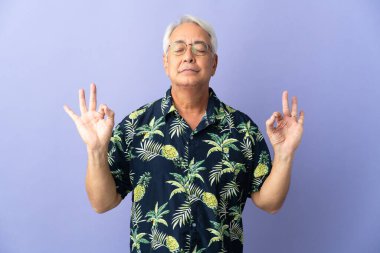 Orta yaşlı Brezilyalı bir adam mor arka planda Zen pozisyonunda izole edilmiş.