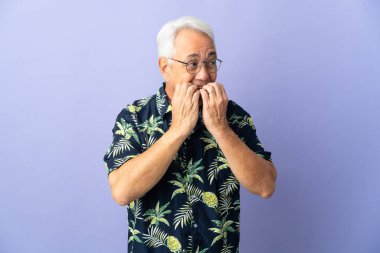 Orta yaşlı Brezilyalı bir adam mor arka planda izole edilmiş gergin ve korkmuş bir şekilde elleriyle suni teneffüs yapıyor.