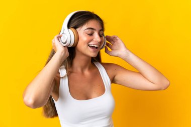 Sarı arka planda izole edilmiş beyaz bir kadın müzik dinliyor ve şarkı söylüyor.