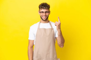 Restoran garsonu, sarı arka planda izole edilmiş sarışın adam işaret parmağıyla işaret etmek harika bir fikir.