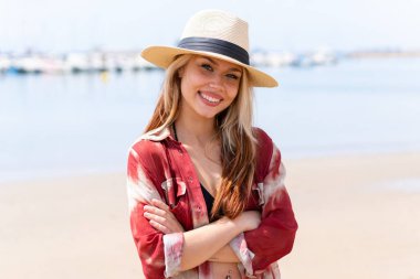 Yaz tatilinde genç ve güzel bir kadın plajda kollarını ön cephede kavuşturuyor.