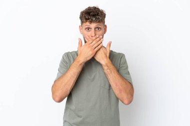 Beyaz arka planda izole edilmiş beyaz tenli yakışıklı bir adam elleriyle ağzını kapatıyor.