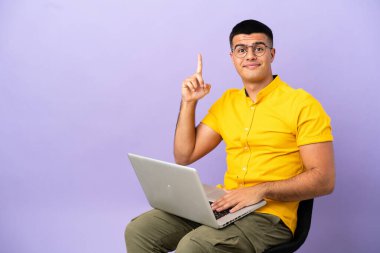 Dizüstü bilgisayarı işaret eden bir sandalyede oturan genç adam harika bir fikir.