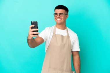 Restoran garsonu, izole edilmiş mavi arkaplanda özçekim yapıyor.