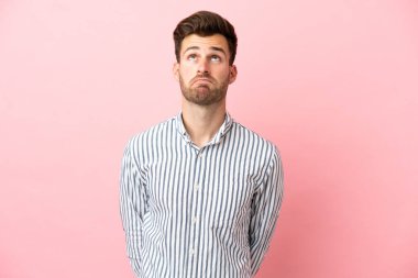 Beyaz tenli yakışıklı adam pembe arka planda izole edilmiş ve yukarı bakıyor.