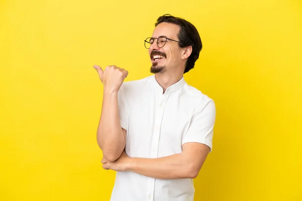 Hombre Joven Caucásico Aislado Sobre Fondo Amarillo Apuntando Hacia Lado — Foto de Stock