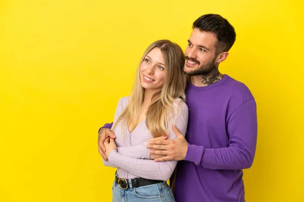 Pareja Joven Sobre Fondo Amarillo Aislado Mirando Hacia Lado —  Fotos de Stock