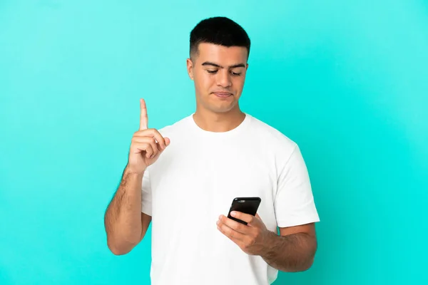 Jovem Homem Bonito Sobre Fundo Azul Isolado Usando Telefone Celular — Fotografia de Stock