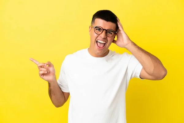 Jovem Homem Bonito Sobre Isolado Fundo Amarelo Surpreso Apontando Dedo — Fotografia de Stock