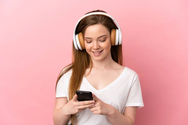 Teenager Girl Isolated Pink Background Listening Music Looking Mobile — Stock Photo, Image