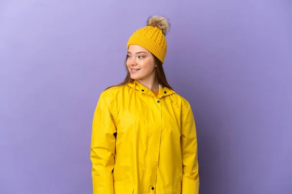 Chica Adolescente Con Abrigo Impermeable Sobre Fondo Púrpura Aislado Mirando —  Fotos de Stock