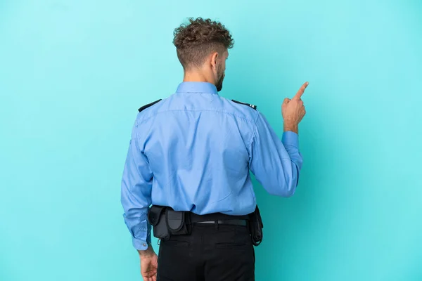 Młody Policjant Blondynka Człowiek Odizolowany Biały Niebieskim Tle Wskazując Powrotem — Zdjęcie stockowe