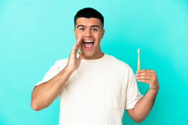Jovem Homem Bonito Escovando Dentes Sobre Fundo Azul Isolado Gritando — Fotografia de Stock