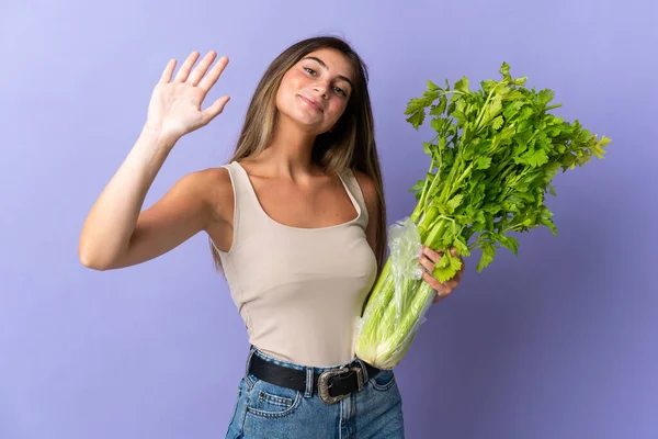 Young Woman Holding Celery Isolated Purple Background Saluting Hand Happy — Stock Photo, Image