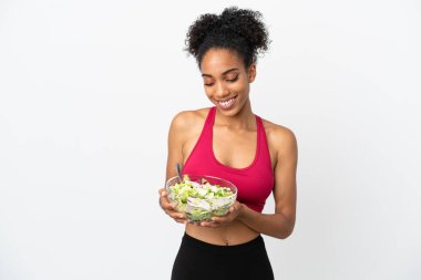 Beyaz arka planda salatalı genç Afrikalı Amerikalı kadın elinde mutlu bir ifadeyle bir kase salata tutuyor.