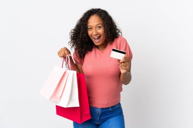 Beyaz arka planda izole edilmiş genç bir Kübalı kız elinde alışveriş torbaları ve şaşırmış