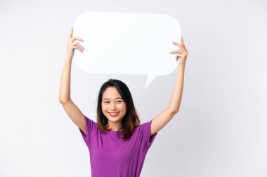 Beyaz arka planda izole edilmiş genç Vietnamlı kadın boş bir konuşma balonu tutuyor.