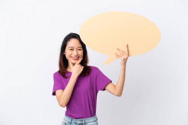 Beyaz arka planda izole edilmiş genç Vietnamlı bir kadın boş bir konuşma balonu tutuyor ve onu işaret ediyor.