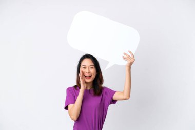 Beyaz arka planda izole edilmiş genç Vietnamlı bir kadın boş bir konuşma balonu tutuyor ve bağırıyor.