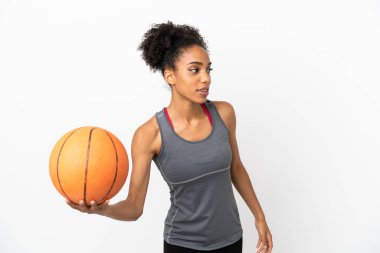 Genç basketbolcu Latin kadın, beyaz arka planda izole edilmiş basketbol oynuyor.