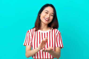 Genç Vietnamlı kadın mavi arka planda izole edilmiş bir konferansta sunumdan sonra alkışlıyor.