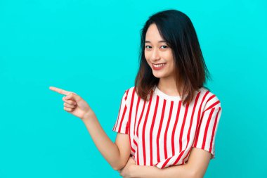 Genç Vietnamlı bir kadın mavi arka planda izole edilmiş.