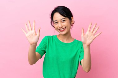 Pembe arka planda izole edilmiş genç Vietnamlı kadın parmaklarıyla ona kadar sayıyor.