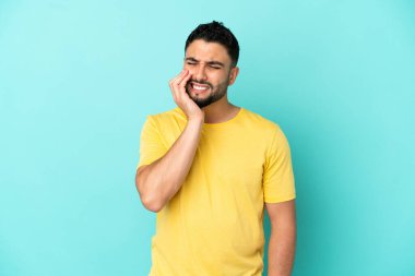 Mavi arka planda diş ağrısı çeken genç bir Arap.