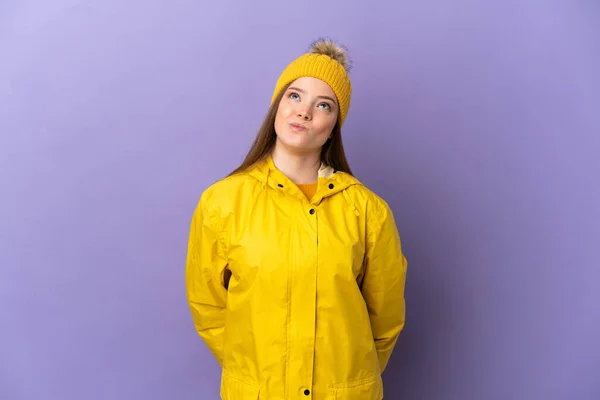 Chica Adolescente Con Abrigo Impermeable Sobre Fondo Púrpura Aislado Mirando —  Fotos de Stock