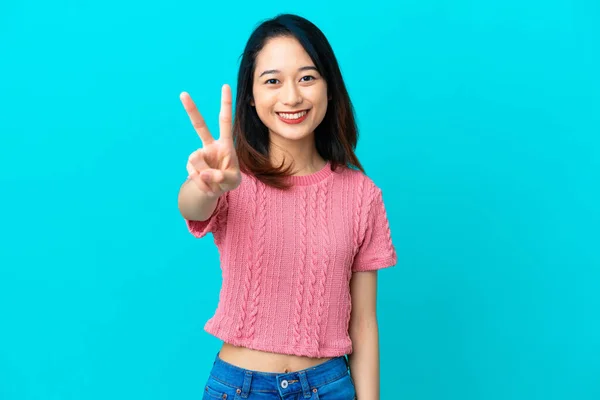 Νεαρή Βιετναμέζα Γυναίκα Απομονωμένη Μπλε Φόντο Χαμογελώντας Και Δείχνοντας Σημάδι — Φωτογραφία Αρχείου