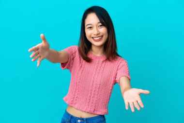 Mavi arka planda izole edilmiş genç Vietnamlı kadın sunar ve davet eder.