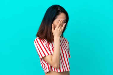 Genç Vietnamlı kadın mavi arka planda izole edilmiş, baş ağrısı var.