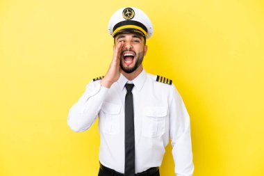 Arap uçak pilotu sarı arka planda izole edilmiş ve ağzı açık bağırıyor.