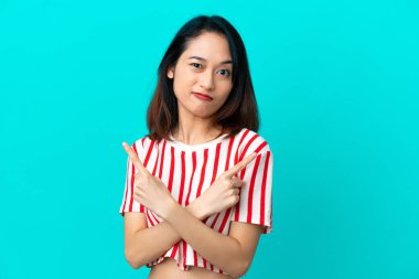 Genç Vietnamlı kadın mavi arka planda izole edilmiş. Yan taraftakilerin şüphelerine işaret ediyor.