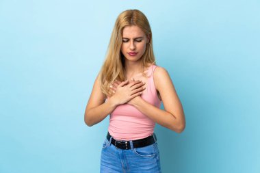 Genç Uruguaylı sarışın kadın soyutlanmış mavi arka planda, kalbinde bir ağrı var.