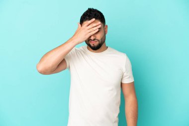 Genç Arap adam mavi arka planda baş ağrısı ile izole edildi.