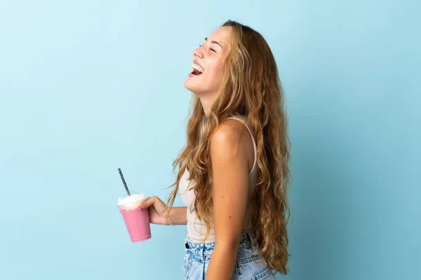 Ung Kvinna Med Jordgubbsmjölkshake Isolerad Blå Bakgrund Skrattar Sidoläge — Stockfoto