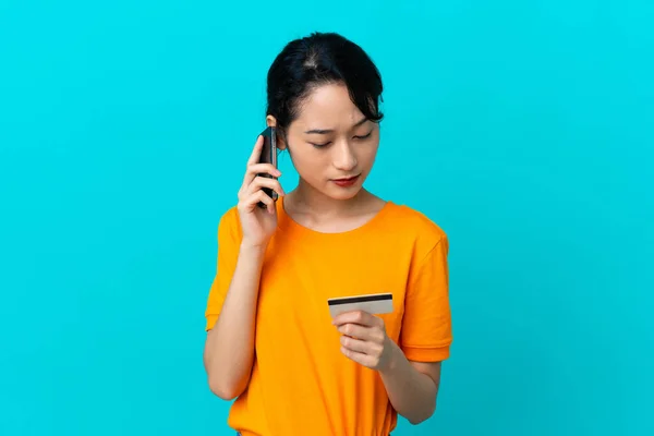Jonge Vietnamese Vrouw Geïsoleerd Blauwe Achtergrond Kopen Met Mobiele Telefoon — Stockfoto