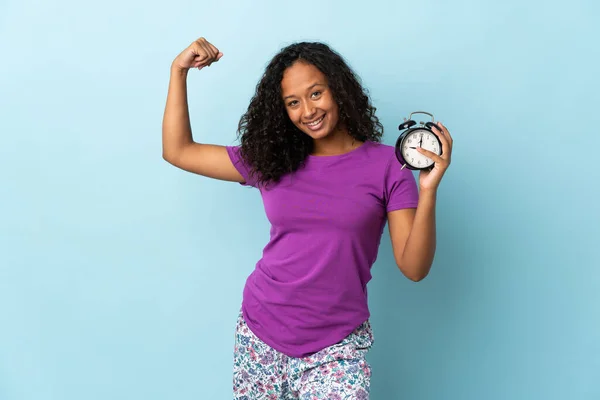 Teenager Cuban Girl Isolated Blue Background Pajamas Holding Clock While — Stock Photo, Image