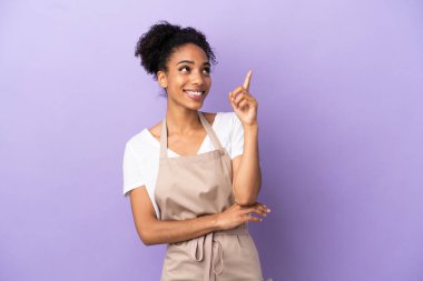 Restoran garsonu, mor arka planda izole edilmiş Latin kadın harika bir fikre işaret ediyor.