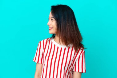 Genç Vietnamlı kadın mavi arka planda izole edilmiş.